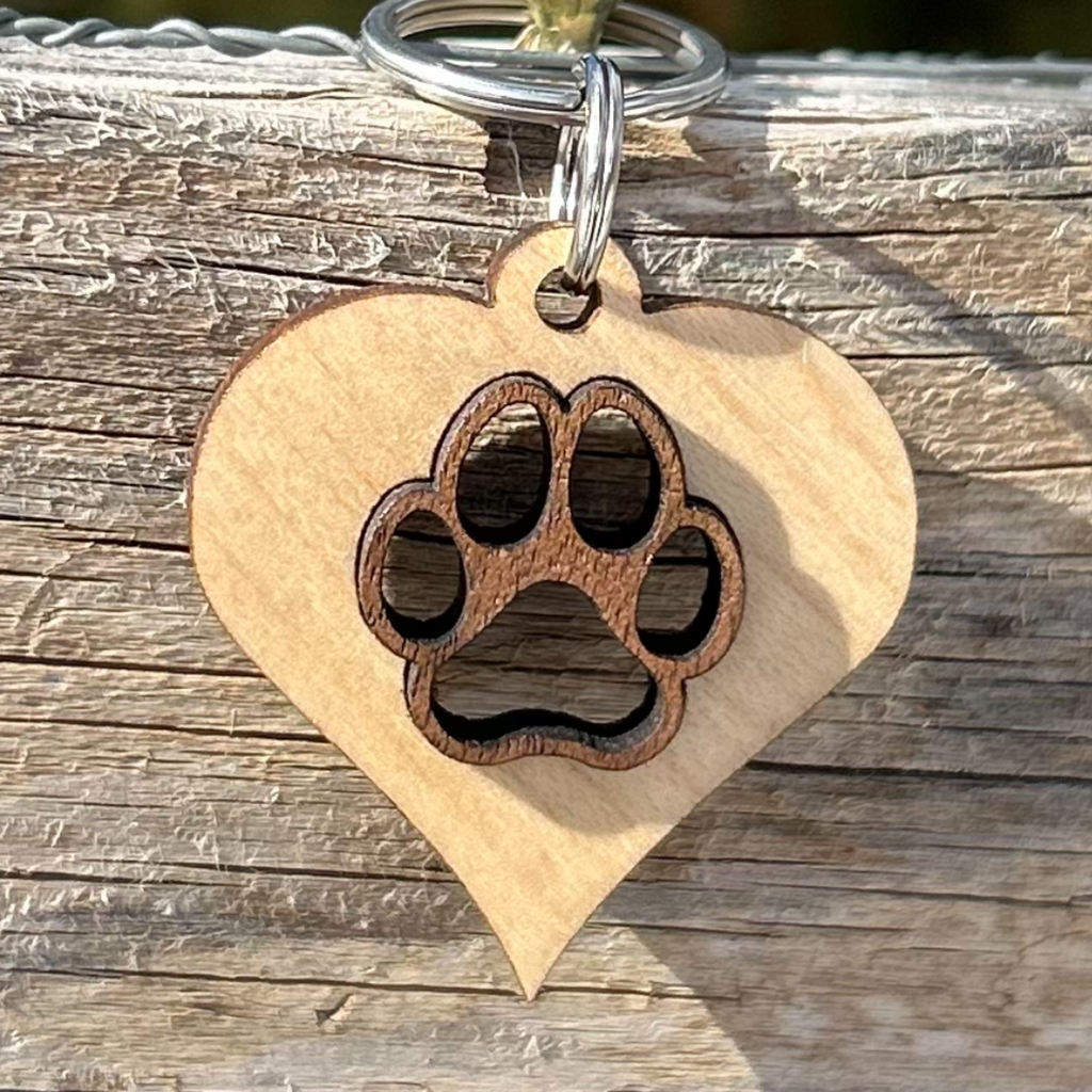 Solid maple wood heart with a solid laser cut walnut wood paw inlayed in the center. attached to metal split ring that can hang on your dogs collar