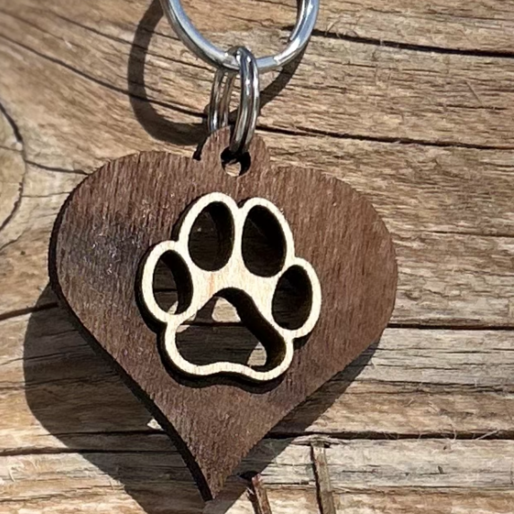 Solid walnut wood heart with a solid laser cut maple wood paw inlayed in the center. attached to metal split ring that can hang on your dogs collar